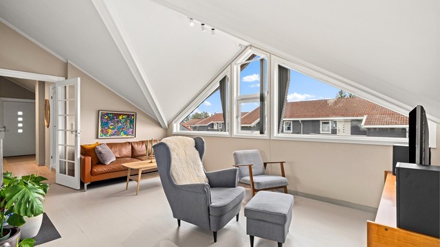 Stuen har en åpen løsning mot kjøkkenet, og de store, karakteristiske vindusflatene gir rikelig med dagslys.