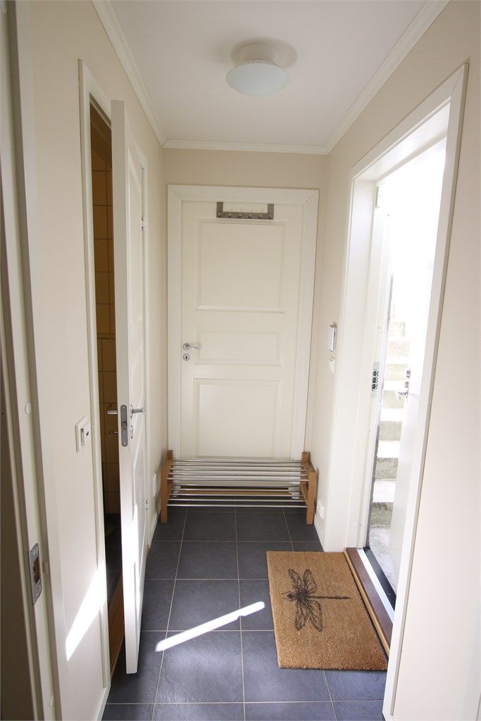 Entré/gang med gulvfliser og egen inngang via utvendig kjellertrapp. Foto: Selgers private bilde