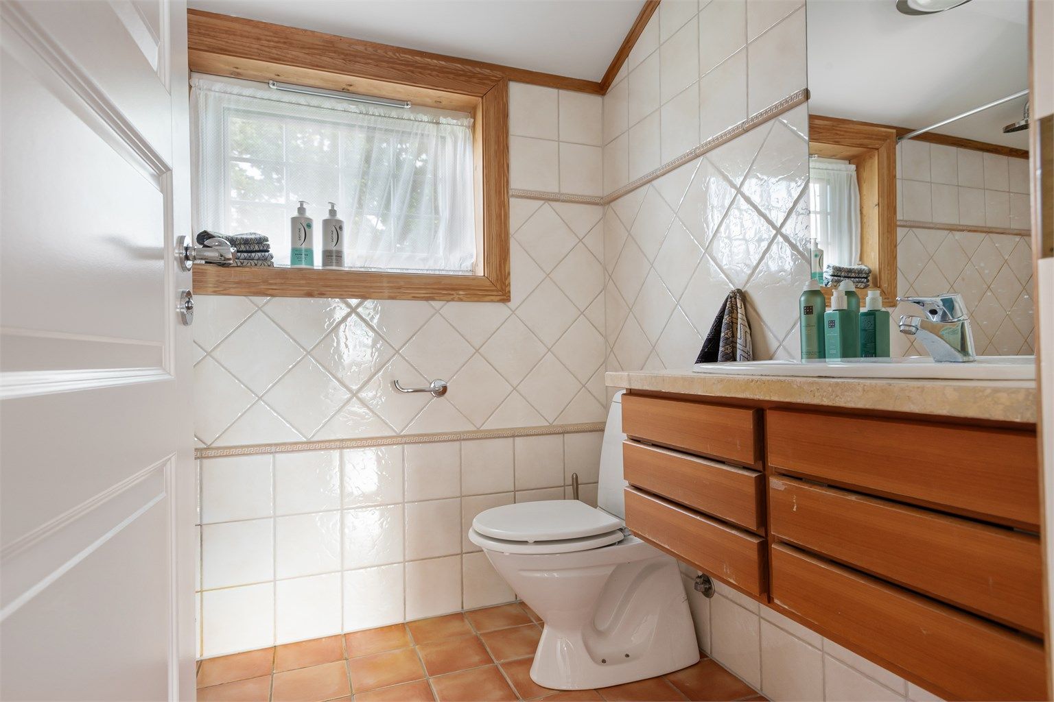 Det andre badet i etasjen ligger i praktisk tilknytning til barnerommene. Vegghengt innredning fra Multiform med heltre fronter og benkeplate av lys stein også her. Dusjhjørne med ett-greps dusjarmatur tilkoblet hånddusj og regnfallsdusj