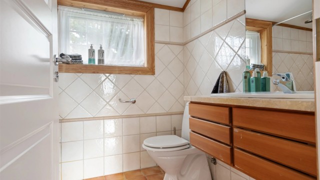 Det andre badet i etasjen ligger i praktisk tilknytning til barnerommene. Vegghengt innredning fra Multiform med heltre fronter og benkeplate av lys stein også her. Dusjhjørne med ett-greps dusjarmatur tilkoblet hånddusj og regnfallsdusj