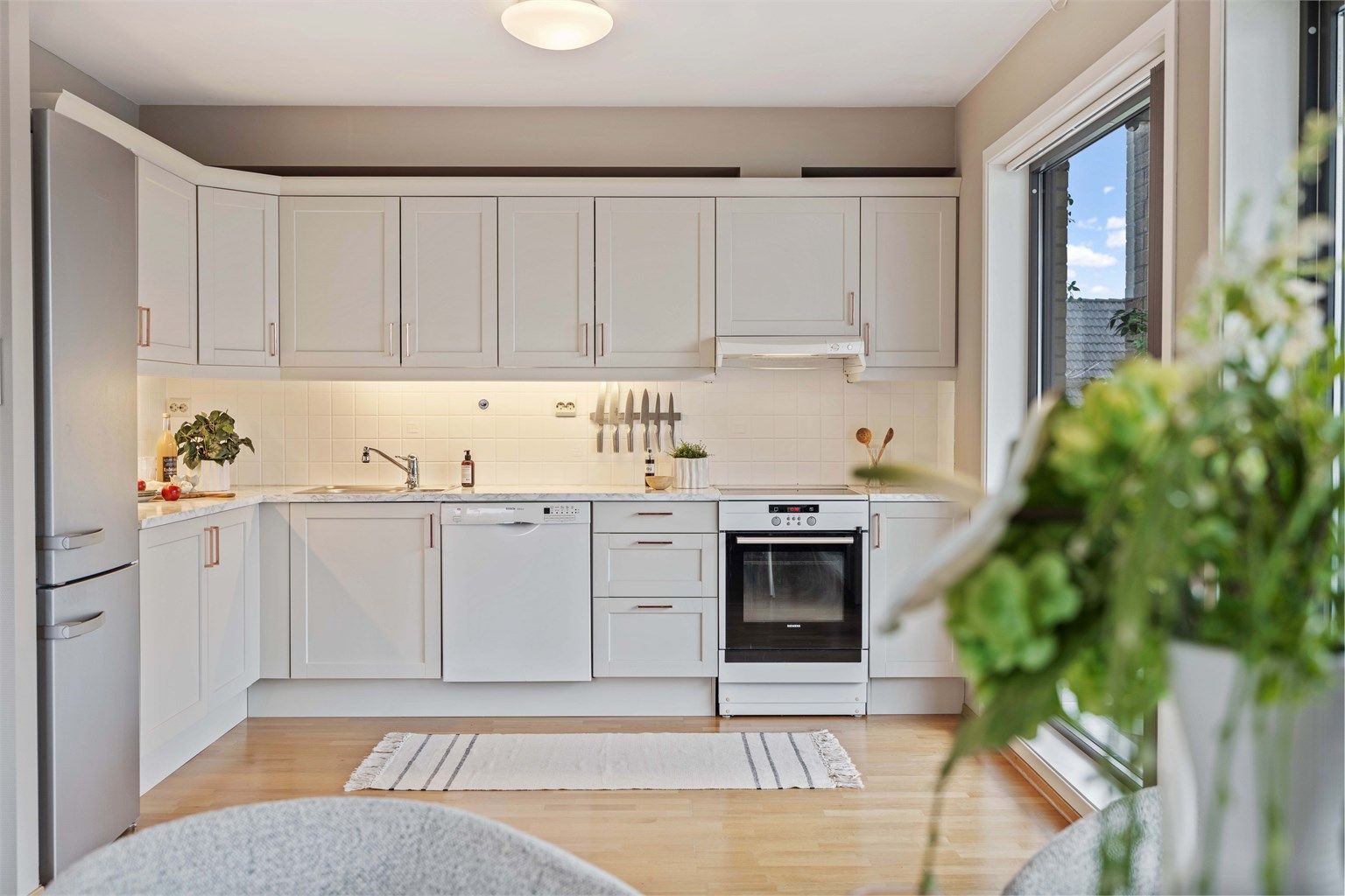 Et funksjonelt og velholdt kjøkken med profilerte fronter og rikelig med skap- og benkeplass.