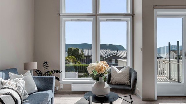 De høye vinduene i stuen slipper inn rikelig med dagslys. Utvendige screens kan justeres etter solforholdene og sørger for behagelig solskjerming ved behov.