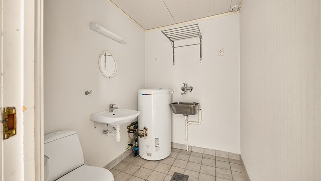 Praktisk vaskerom i første etasje med gulvvarme, gulvstående klosett og opplegg for vaskemaskin/tørketrommel.