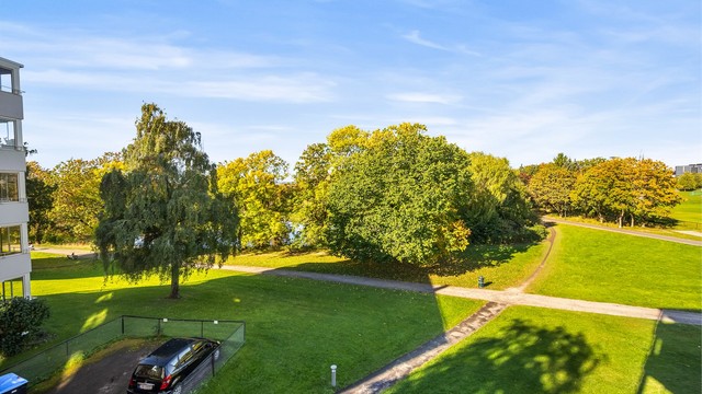 Fra balkongen ser du ut over vide grøntarealer og luftige tretopper som skifter farger med årstidene.