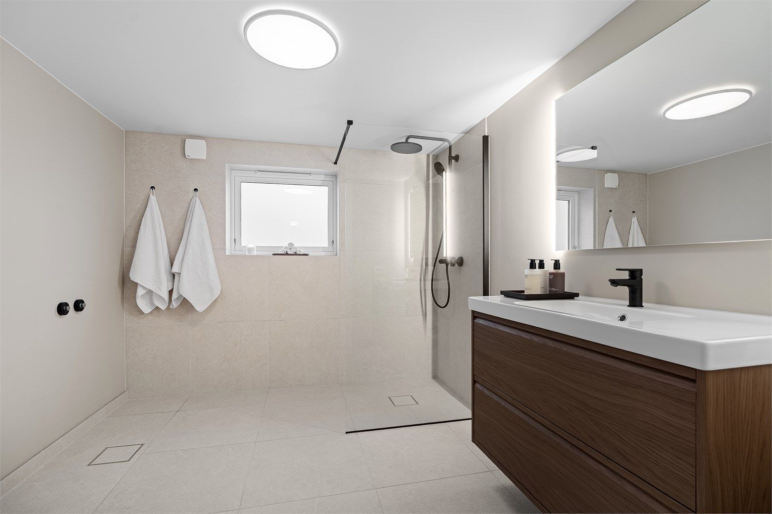 Godt belyst bad med speil med sidelys,  klargjort til badekar