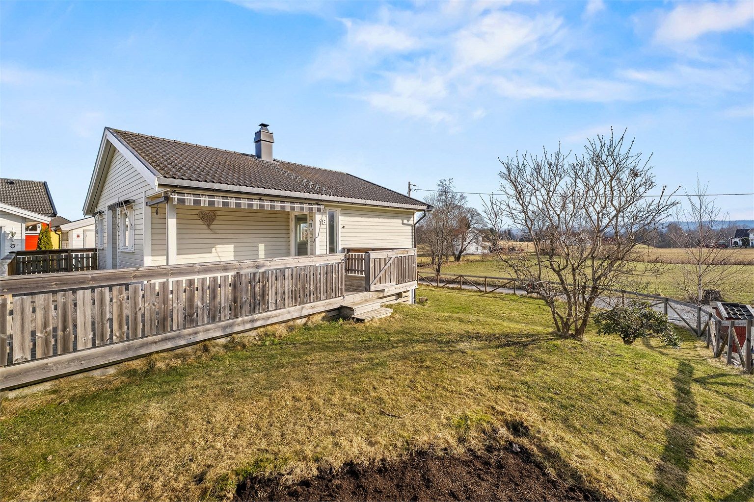 Terrassen strekker seg rundt deler av huset og gir flere soner for utemøbler.