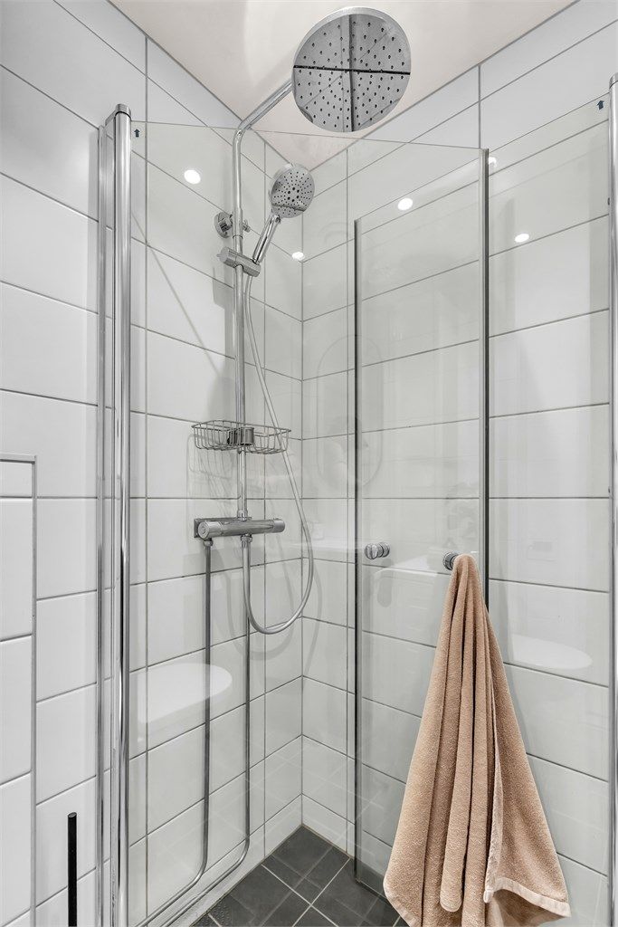 Badet har moderne og tidløse fliser, samt vannfallsdusj med innsvingbare dører.