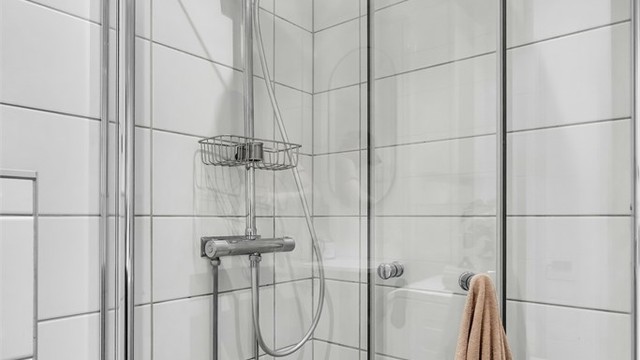 Badet har moderne og tidløse fliser, samt vannfallsdusj med innsvingbare dører.