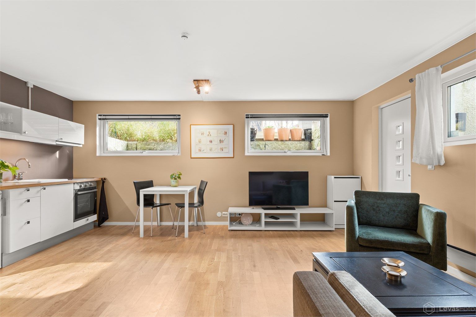 Hybelen har en åpen stue- og kjøkkenløsning med parkett og gulvvarme.