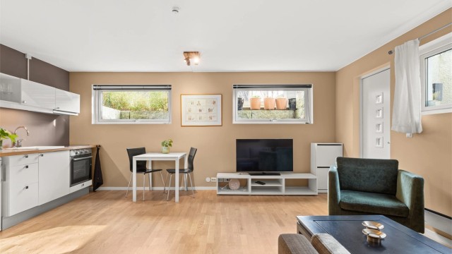 Hybelen har en åpen stue- og kjøkkenløsning med parkett og gulvvarme.