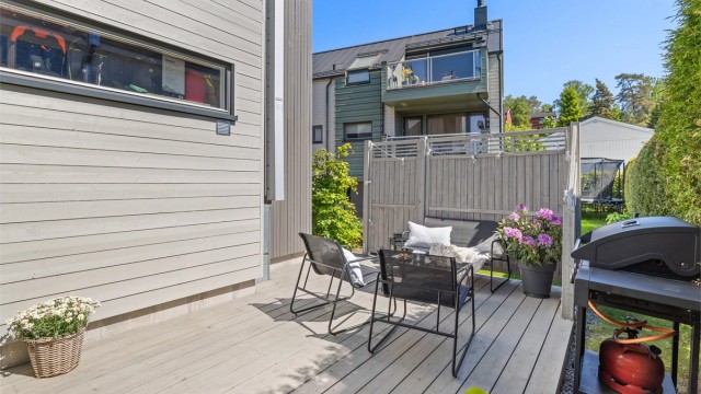 Boligen disponerer en vestvendt terrasseplatting med levegger og tilhørende plenareal på bakkeplan.