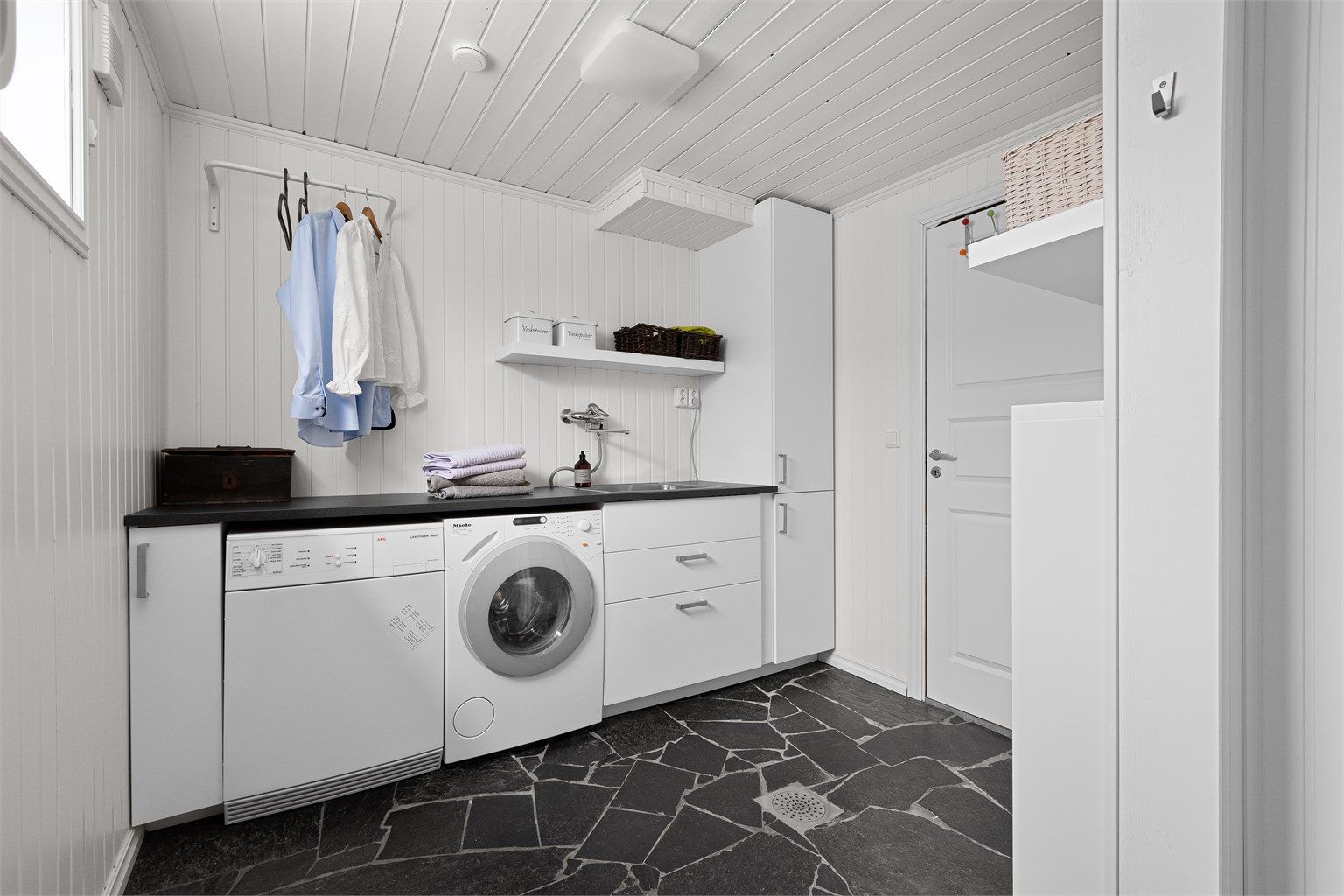 Det er romslig og praktisk vaskerom med plass til både vaskemaskin og tørketrommel. Det er bod i tilgang til vaskerom med god oppbevaringsplass. 
Fra vaskerom er det utgang til trapp opp til gårdsrom, så det kan også brukes som biingang. 