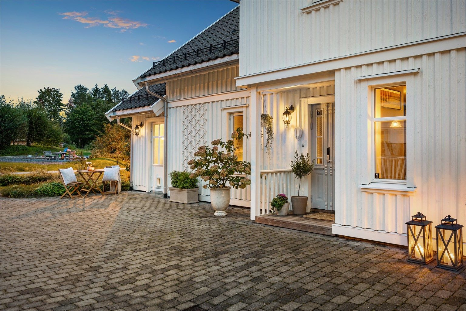 Et innbydende inngangsparti med belegningsstein og overbygg.