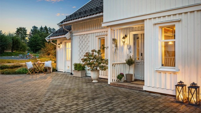 Et innbydende inngangsparti med belegningsstein og overbygg.