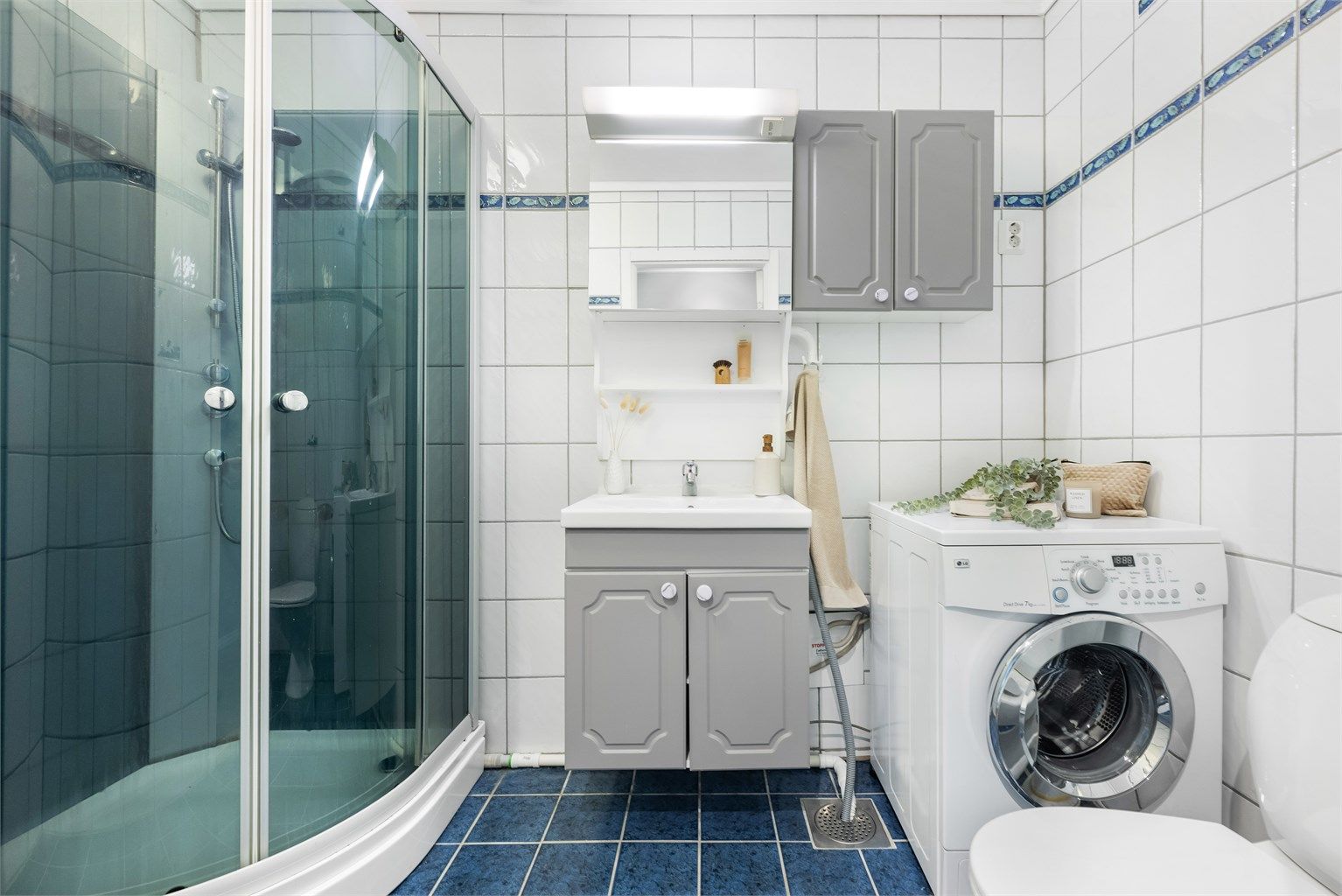 Helfliset baderom med dusjkabinett og opplegg for vaskemaskin. 