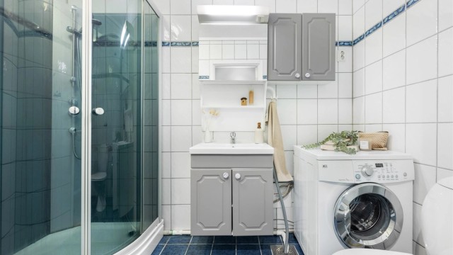 Helfliset baderom med dusjkabinett og opplegg for vaskemaskin.