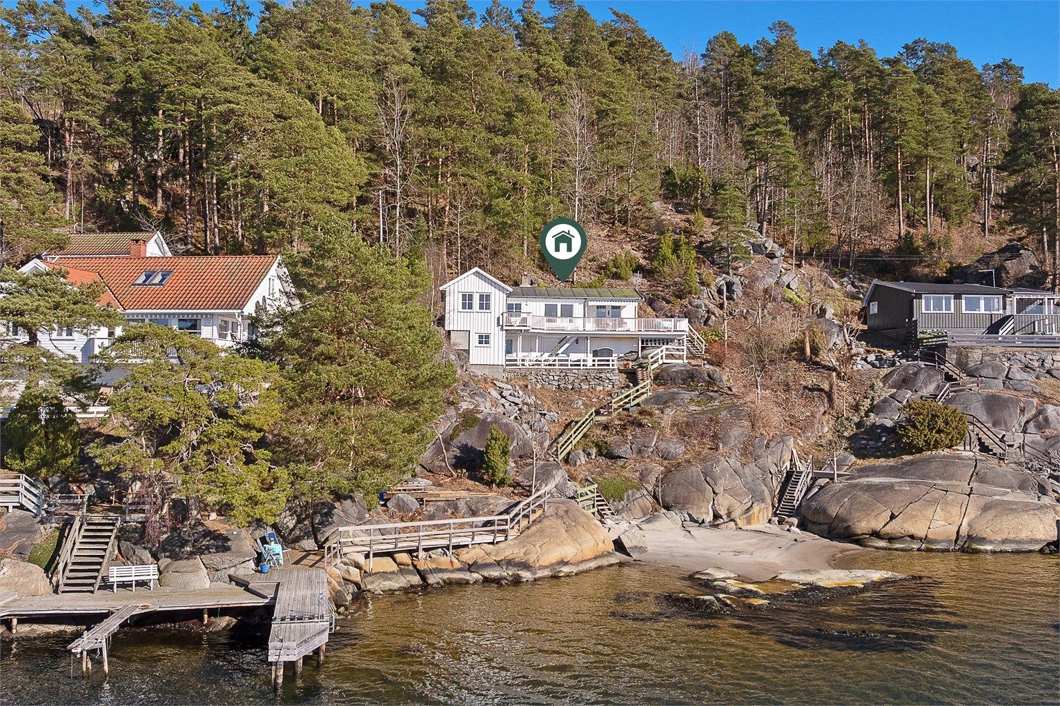 Hytta er hvitmalt og har store uteplasser.