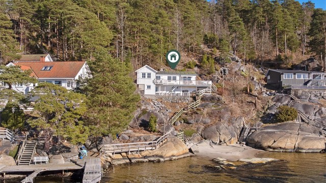 Hytta er hvitmalt og har store uteplasser.