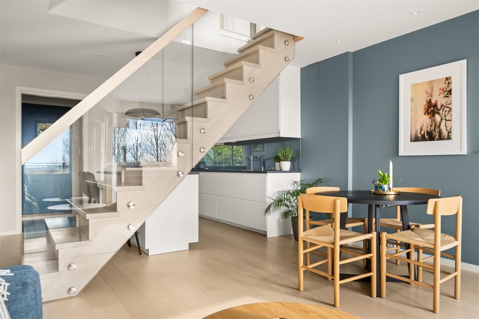 Den innvendige trappen i tre og glass er et sentralt designelement som binder de to etasjene elegant sammen.