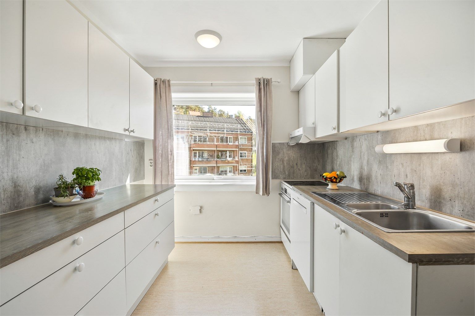 Kjøkken med innredning med glatte fronter. Benkeplate med laminert overflate og nedfelt kjøkkenvask.