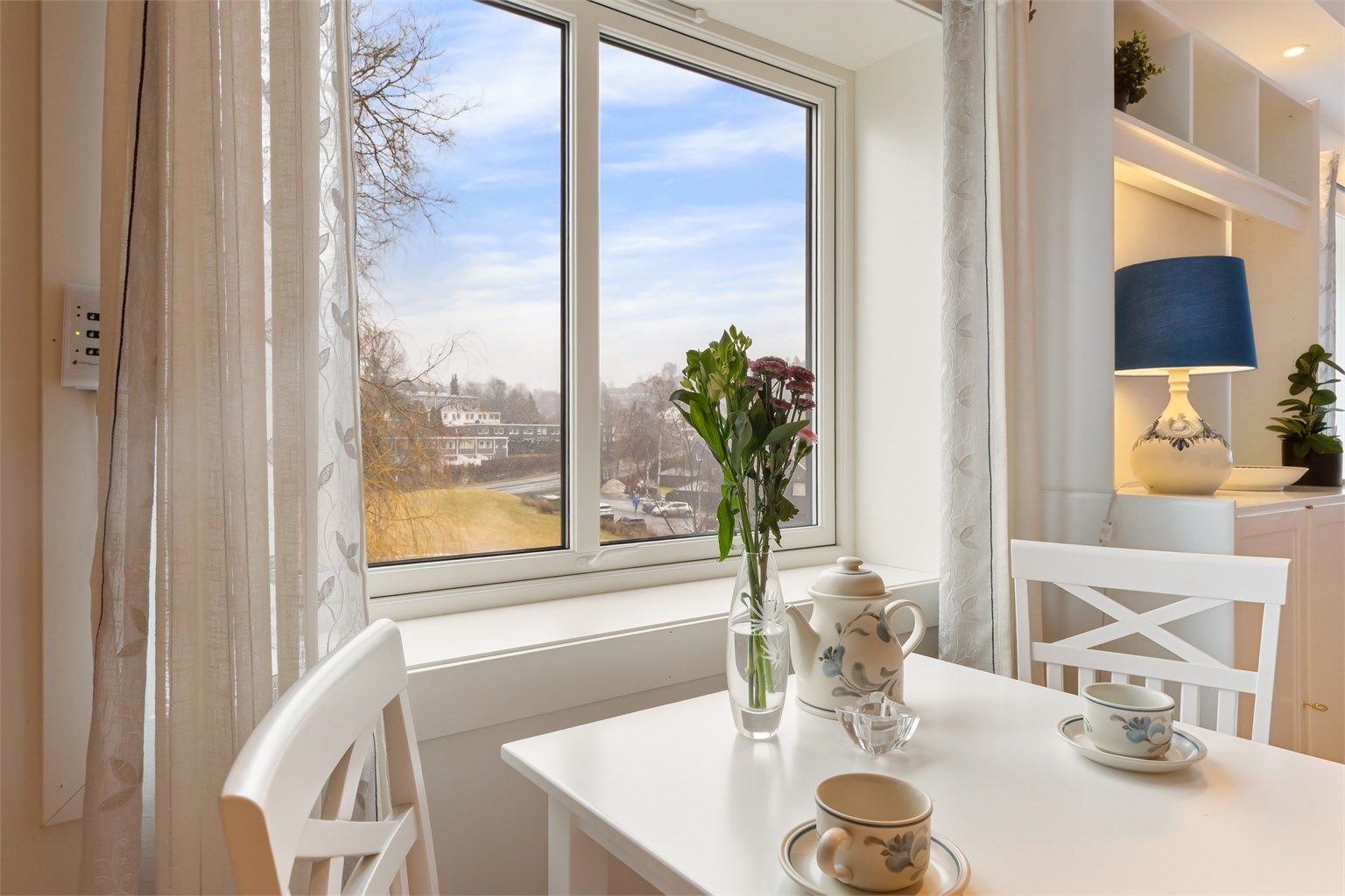 Ved kjøkkenvinduet er det en hyggelig plass for en liten spisegruppe.