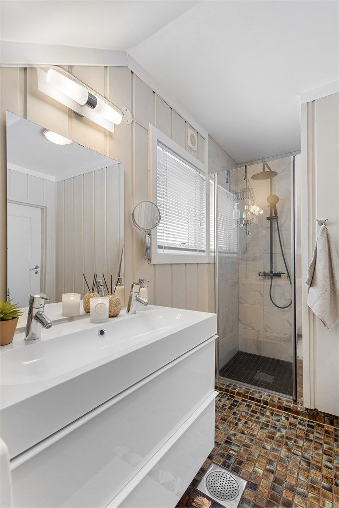 Badet har en dusjnisje med dusjvegg av glass og veggmontert regnfallsdusj