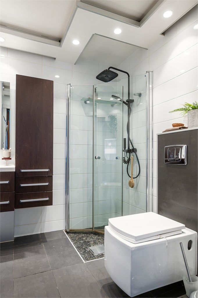 Innredningen består av vegghengt toalett og servantinnredning med speil i tillegg til dusjhjørne med glassdører.