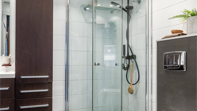 Innredningen består av vegghengt toalett og servantinnredning med speil i tillegg til dusjhjørne med glassdører.