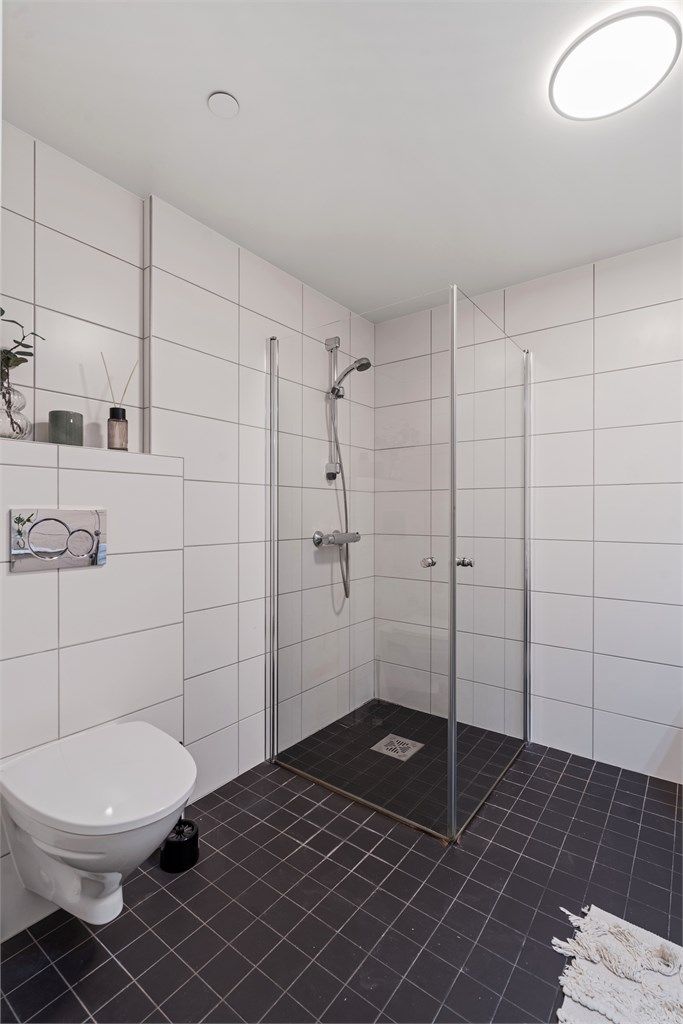 Badet er utstyrt med et praktisk dusjhjørne med innfellbare dører og vegghengt toalett.