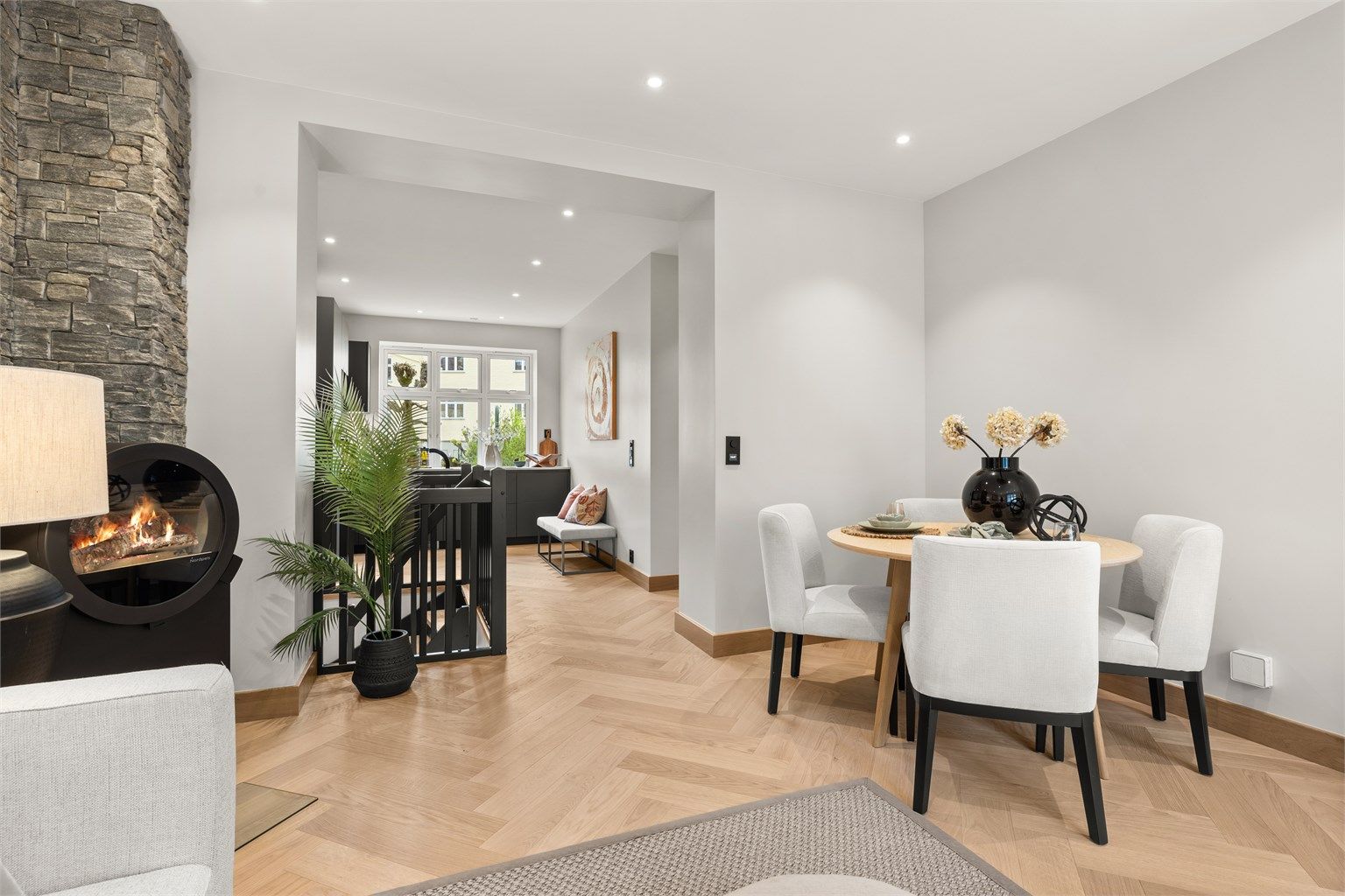 Den lette atmosfæren understrekes av lyse, glatte vegg- og takflater og en gjennomgående planløsning mot kjøkkenet i motsatt ende. 