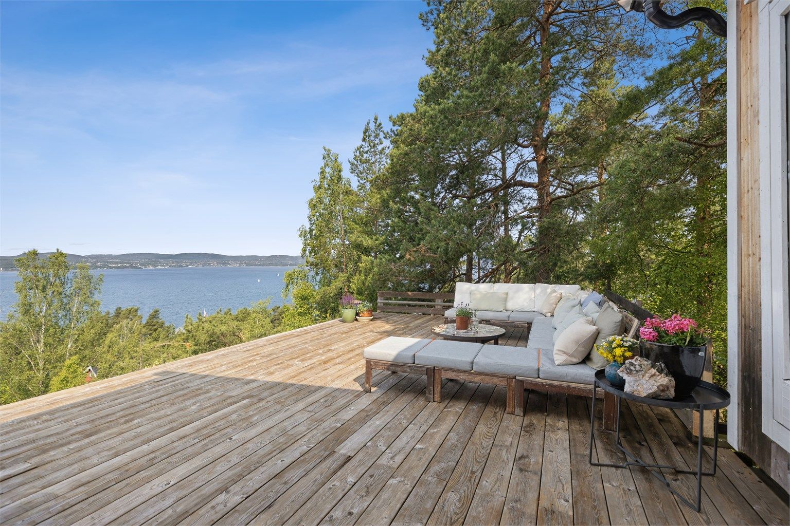 Hytten ligger på en pent opparbeidet tomt på en solrik hylle høyt over sjøen