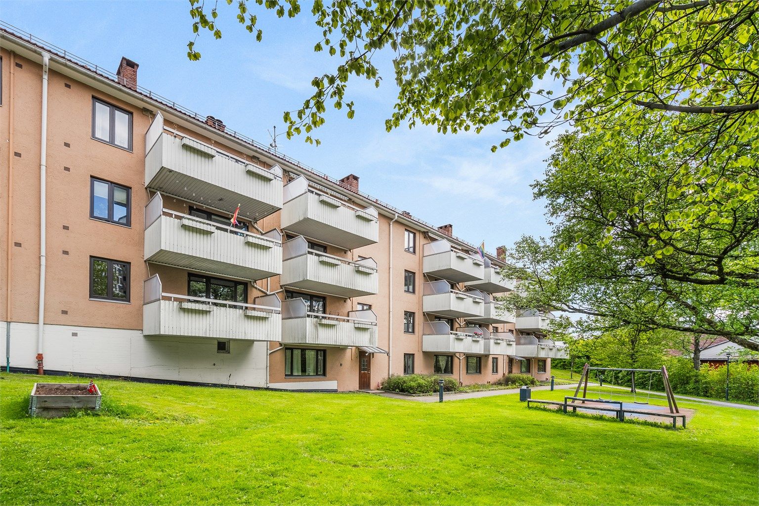 Bygget er omgitt av grønne og velholdte uteområder.