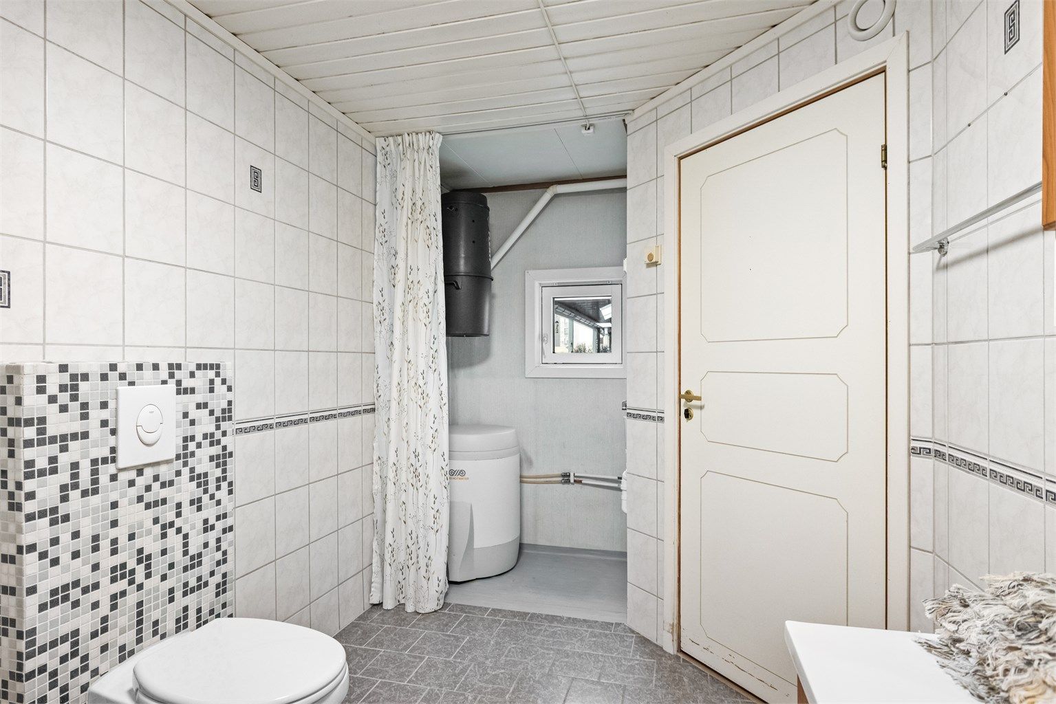 Badet har en praktisk nisje med opplegg for vaskemaskin og plass til varmtvannsbereder.