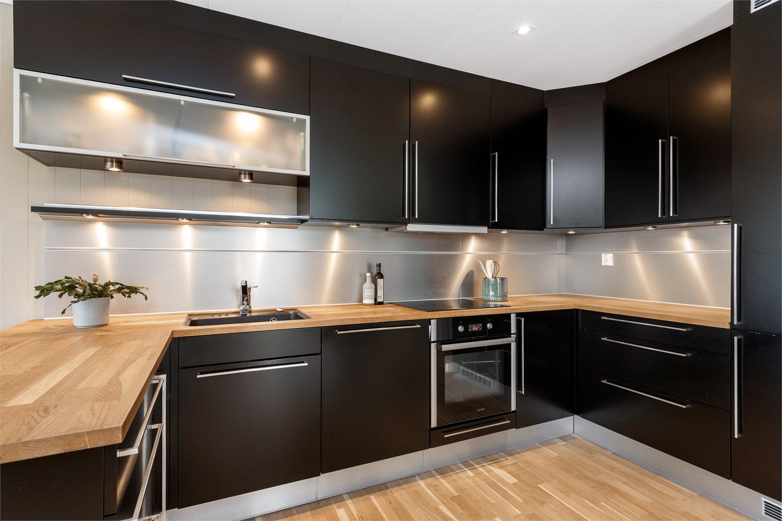 Kjøkkeninnredningen har godt med oppbevarings- og arbeidsplass. Benkeplate av tre. Integrerte hvitevarer inkluderer stekeovn, platetopp, oppvaskmaskin og kjøleskap med fryser.