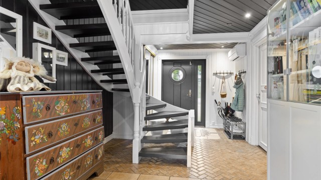 Hall med flislagt gulv med varme. Praktisk oppbevaring i skyvedørsgarderobe. Varmepumpe montert i 2024.