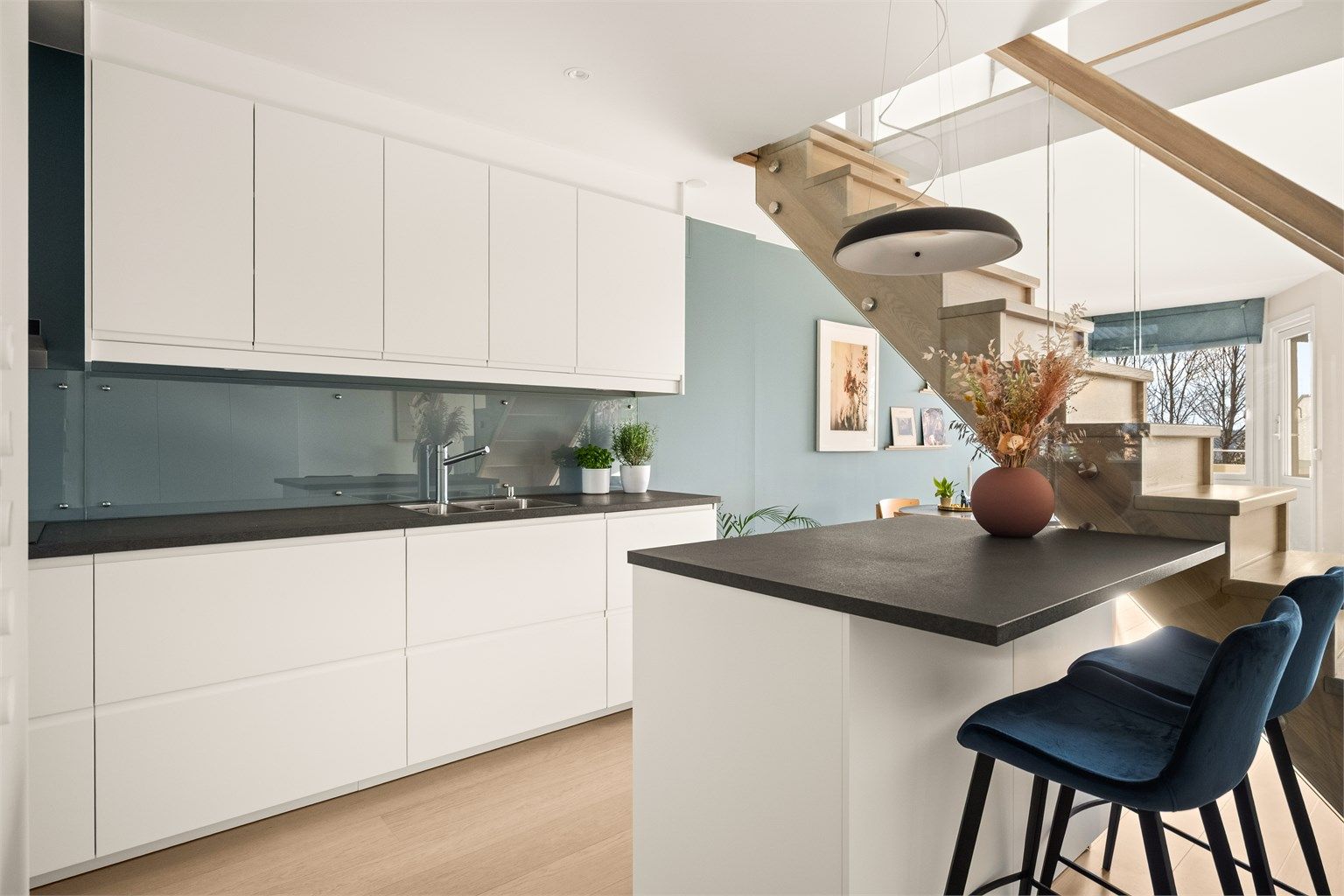 Trappen med glassrekkverk bidrar til å bevare åpenheten og lyset mellom rommene.