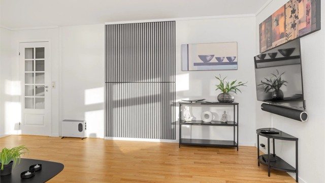Stuen har god plass til møblering og det er montert opp kontrastfelt med gråe spiler, som går igjen flere steder i leiligheten
