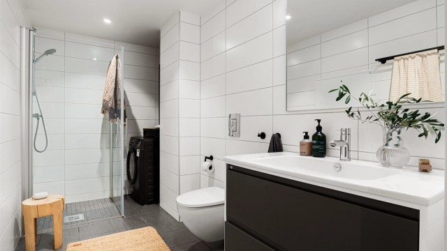 Badet fremstår moderne og stilrent med delikate flislagte vegger og gulv. Vannbåren gulvvarme sørger for god komfort, mens himling med malte plater og innfelte downlights gir behagelig belysning.