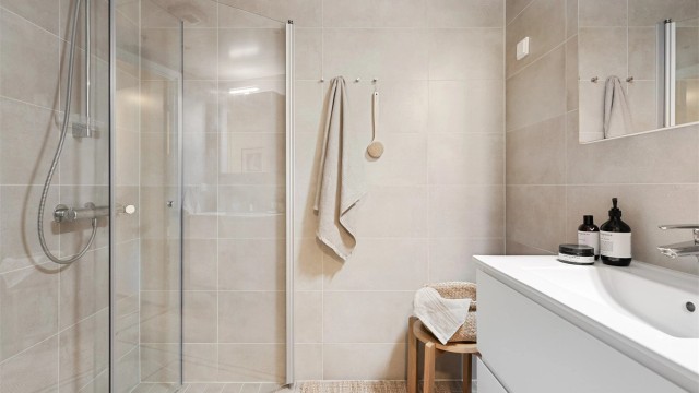 Badet er utstyrt med vegghengt servantinnredning og speilskap med overlys. Dusjhjørne med dører og vegghengt dusjarmatur.