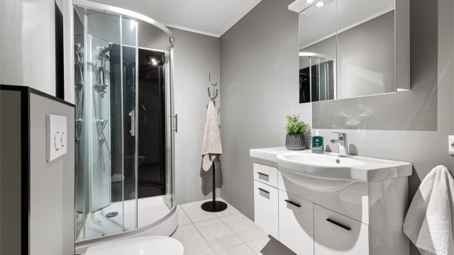 Badet i første etasje har flislagt gulv med gulvvarme, dusjkabinett og vegghengt toalett.