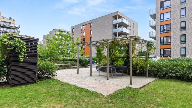 Gjennomarbeidede fellesområder med pergolaer, beplantning og hyggelige møteplasser for beboerne.