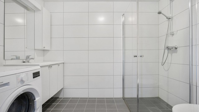 Flislagt bad fra byggeåret med gulvvarme, vegghengt toalett og dusjhjørne med innfellbare glassdører.
