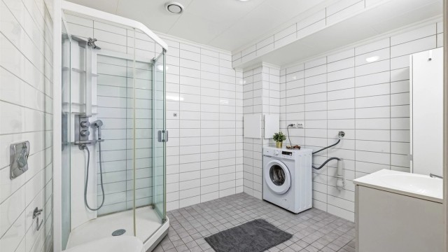Stort, kombinert bad og vaskerom i underetasjen. Rommet er utstyrt med gulvvarme, dusjkabinett og opplegg for vaskemaskin og tørketrommel.