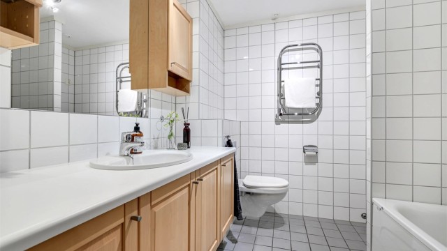 Badet tilhørende hovedsoverom er Innredet med dusj/badekar, servant og vegghengt klosett.