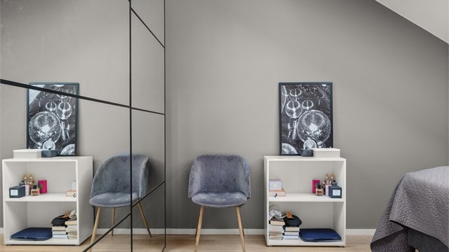 Soverommet fremstår som både praktisk og innbydende, med enstavs parkettgulv, stor skyvedørsgarderobe og integrert belysning i form av downlights.
