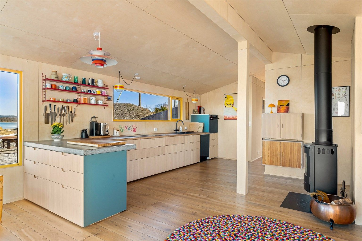 Kjøkkeninnredningen er moderne i sitt formspråk, åpne hyller og et panoramavindu er satt inn istedenfor overskap.