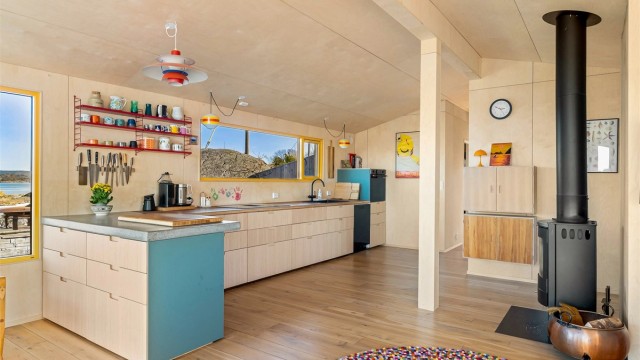 Kjøkkeninnredningen er moderne i sitt formspråk, åpne hyller og et panoramavindu er satt inn istedenfor overskap.