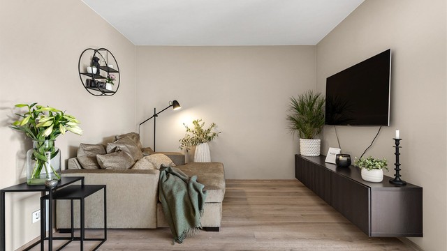 Romslig stue med plass til sittegrupper, TV-område og spisebord.