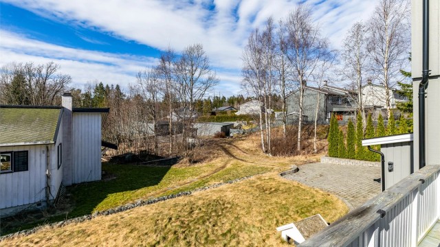 Utsyn over hagen fra terrassen. Adkomst skjer i dag over grøntareal. Eiendommen har tinglyst bruksrett til parkeringsplass i felles garasjerekke nedenfor.