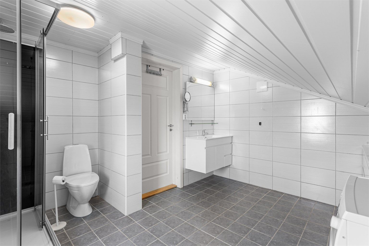 Utleiedel i 2. etasje: Flislagt bad med gulvvarme. Innredet med vegghengt servantinnredning og ovenpåliggende servant. Dusjkabinett og gulvstående toalett. Opplegg for vaskemaskin.